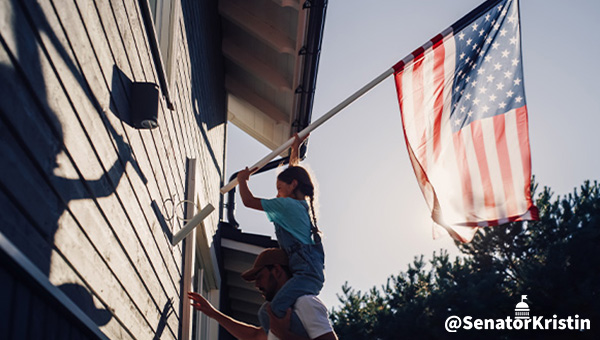 A young girl anchoring an American flag next to her house