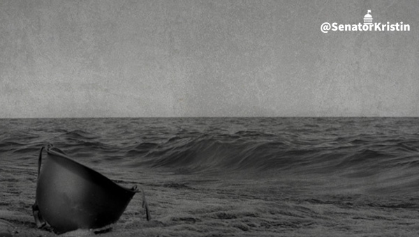 Black and white photo of a WWII era military helmet on an ocean beach
