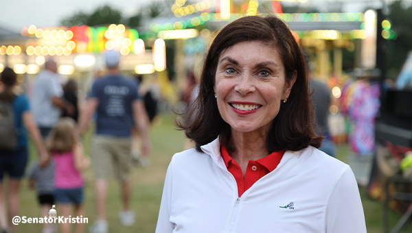 Senator Phillips-Hill standing in front of carnival rides and games.