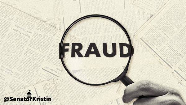 A magnifying glass showing the word “FRAUD” atop documents.