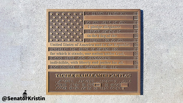 A plaque in the shape of the United States flag with the Pledge of Allegience in braille.